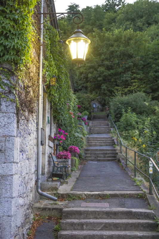 scalinata antica con lampione acceso e fiori fuxia