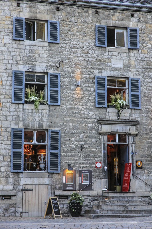 facciata antica di ristorante con finestre con vasi di fiori e insegna