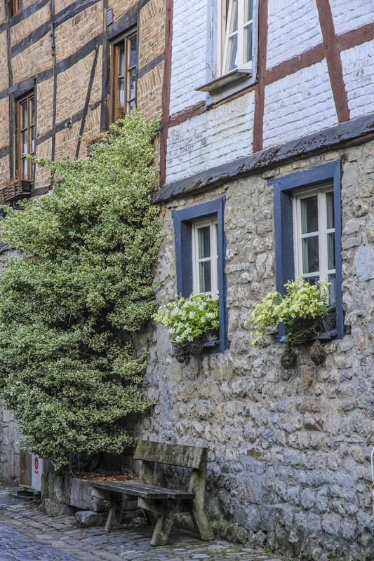 facciata in pietra di casa atica con panchina e vasi di fiori bianchi alle finestre