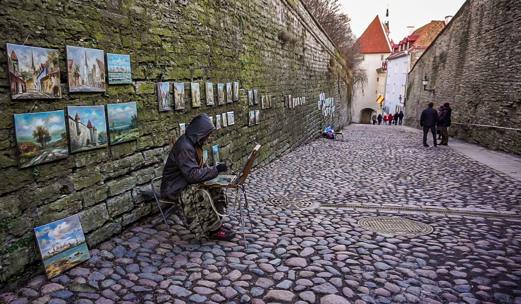 Artista di strada con quadri della città