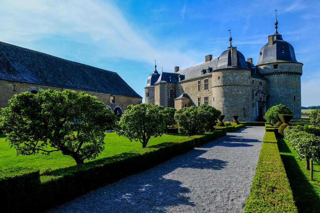 cortile esterno con alberi bassi e aiuole vista su castello in lontananza