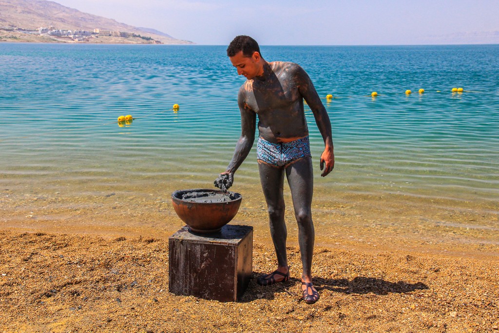 uomo si spalma di fanghi sulla costa del mar morto