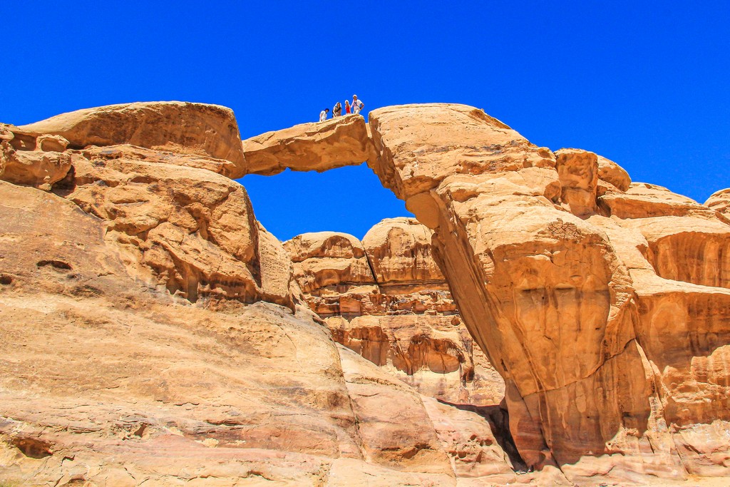 Guida al Wadi Rum arco di roccia con persone su