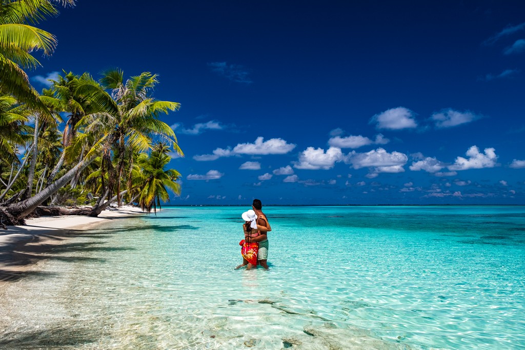 Polinesia Francese fai da te coppia in una spiaggia con palme guarda indietro