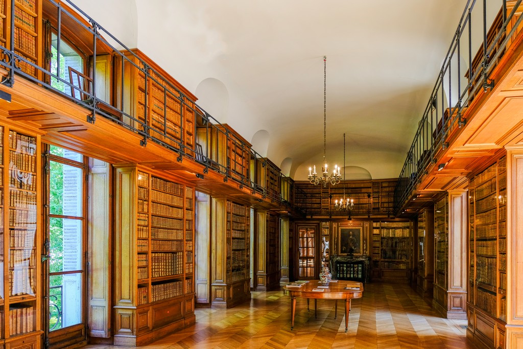 biblioteca con libri su tutti i lati soffitto crema e lampadari