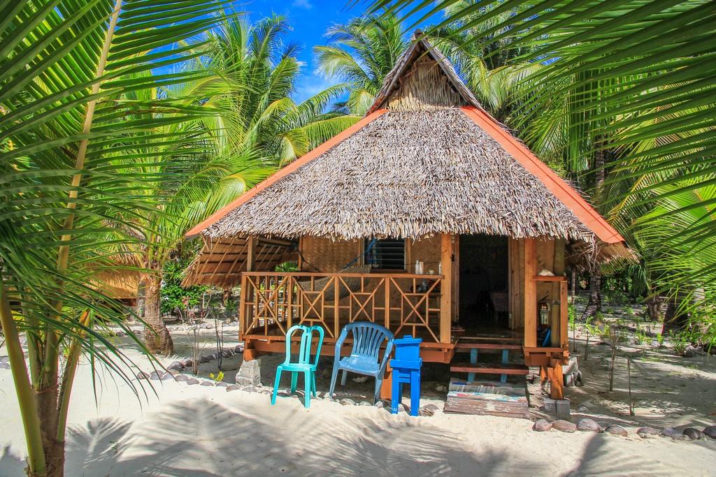 bungalow con sedie di plastica davanti sotto le palme