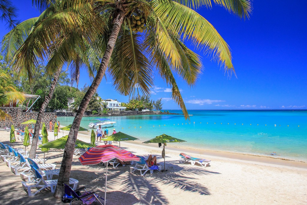 spiaggia di sabbia bianca e mare azzurro con palme e ombrelloni