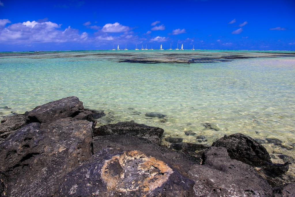 acqua azzurra con barche e sasso in primo piano