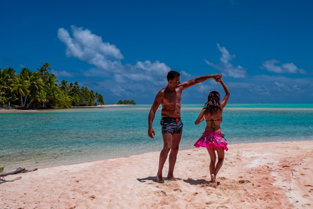 isola di sabbia rosa con palme e coppia che balla