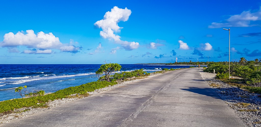 guida a Rangiroa,, strada con oceano a lato e nuvole