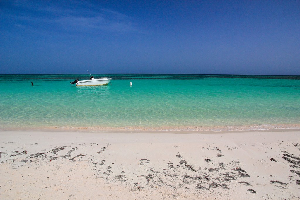 spiaggia di sabbia bianca con mare turchese e barca