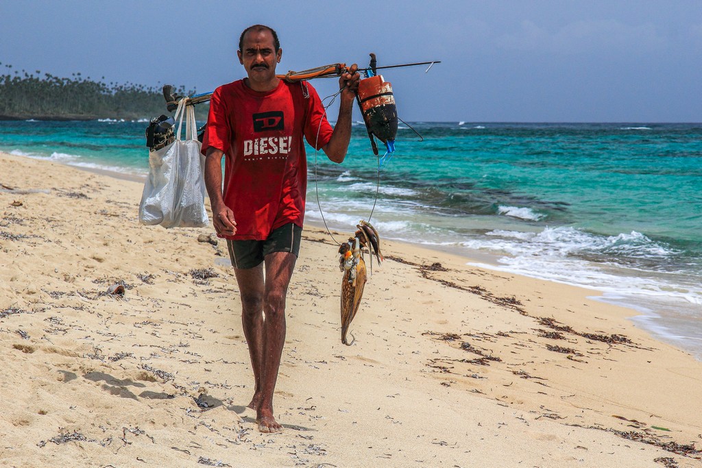 pescatore con pesci in spiaggia di sabbia bianca con mare turchese