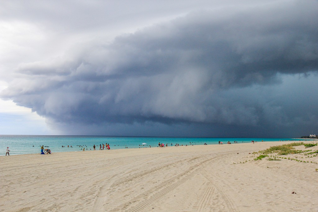 spiaggia di sabbia bianca con mare turchese con nuvola temporalesca