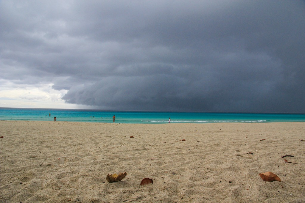 spiaggia di sabbia bianca con mare turchese con nuvola temporalesca