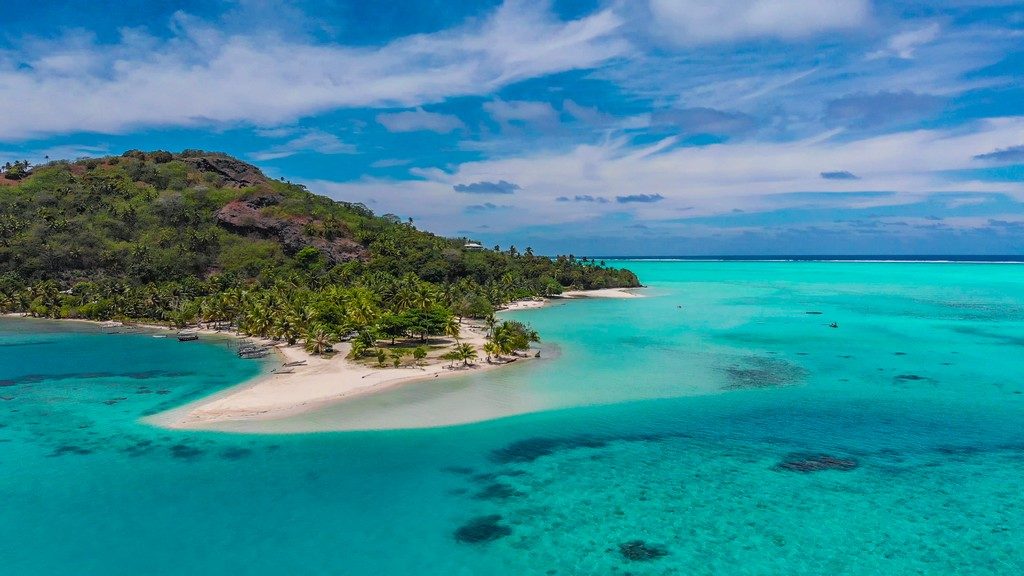 vista aerea di una spiaggia con mare turchese e isola collinare