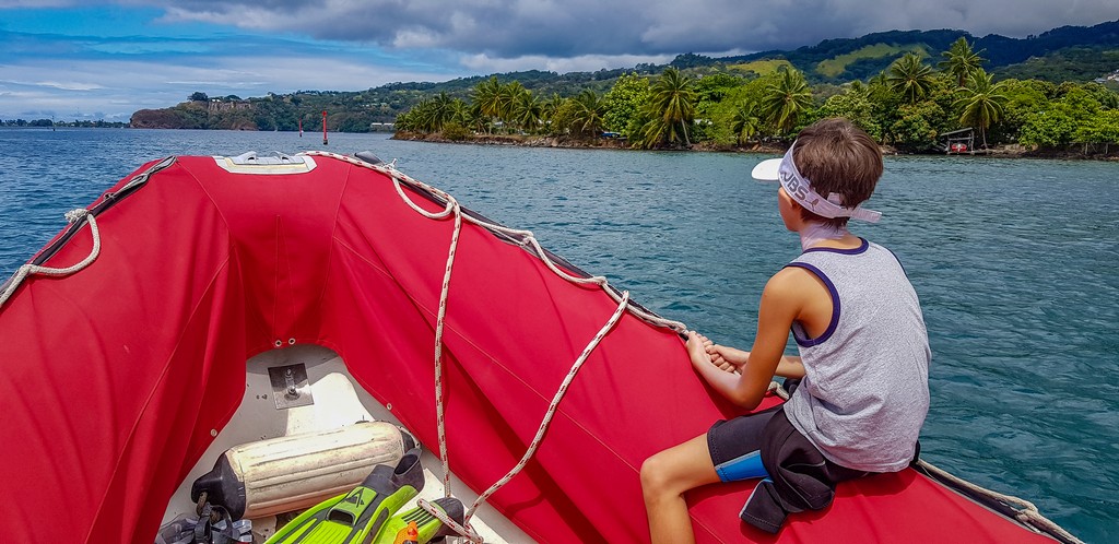 bambino cavalca un gommone rosso al largo della costa nord di Tahiti