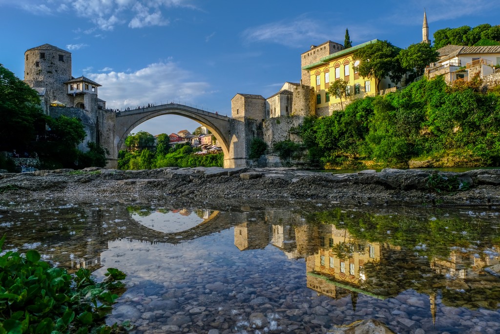 Cosa vedere a Mostar ponte vecchio di mostar riflesso in una pozza dacqua sulle rive