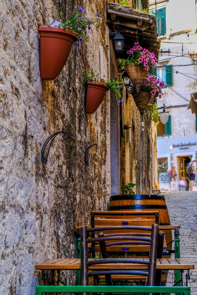 vietta con botti e vasi di fiori