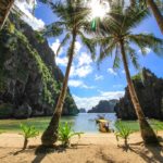 spiaggia con mare cristallino e montagne e palme