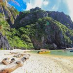 spiaggia bianca con tronchi barche e montagne