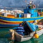 marsaxlokk in inverno barche illuminate dal sole con cielo nuvoloso