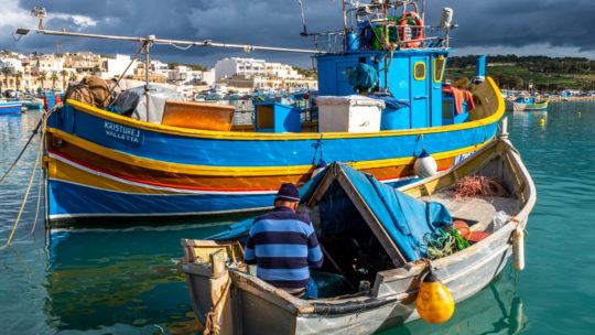 marsaxlokk in inverno barche illuminate dal sole con cielo nuvoloso