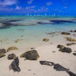 spiagge con sabbia bianca massi e barchette in lontananza