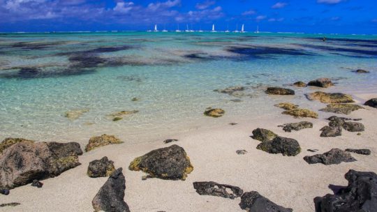 spiagge con sabbia bianca massi e barchette in lontananza