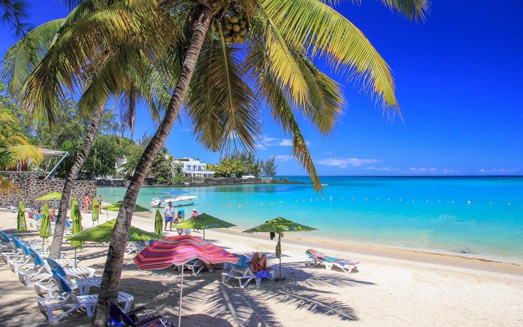 spiaggia di sabbia bianca e mare azzurro con palme e ombrelloni